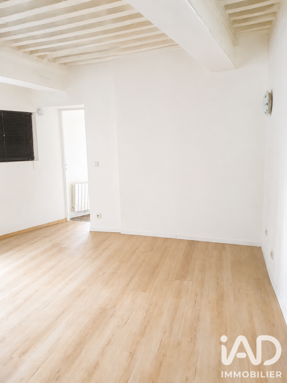 Pièce à vivre du second T2 avec sol clair et plafond à poutres apparentes