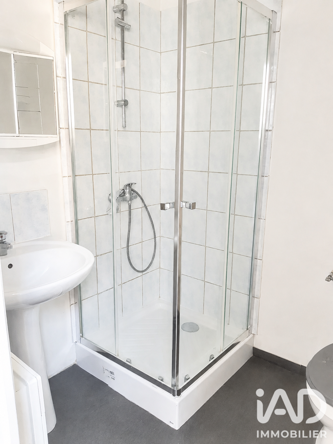 Salle d'eau du second T2 avec cabine douche d'angle et faïence blanche