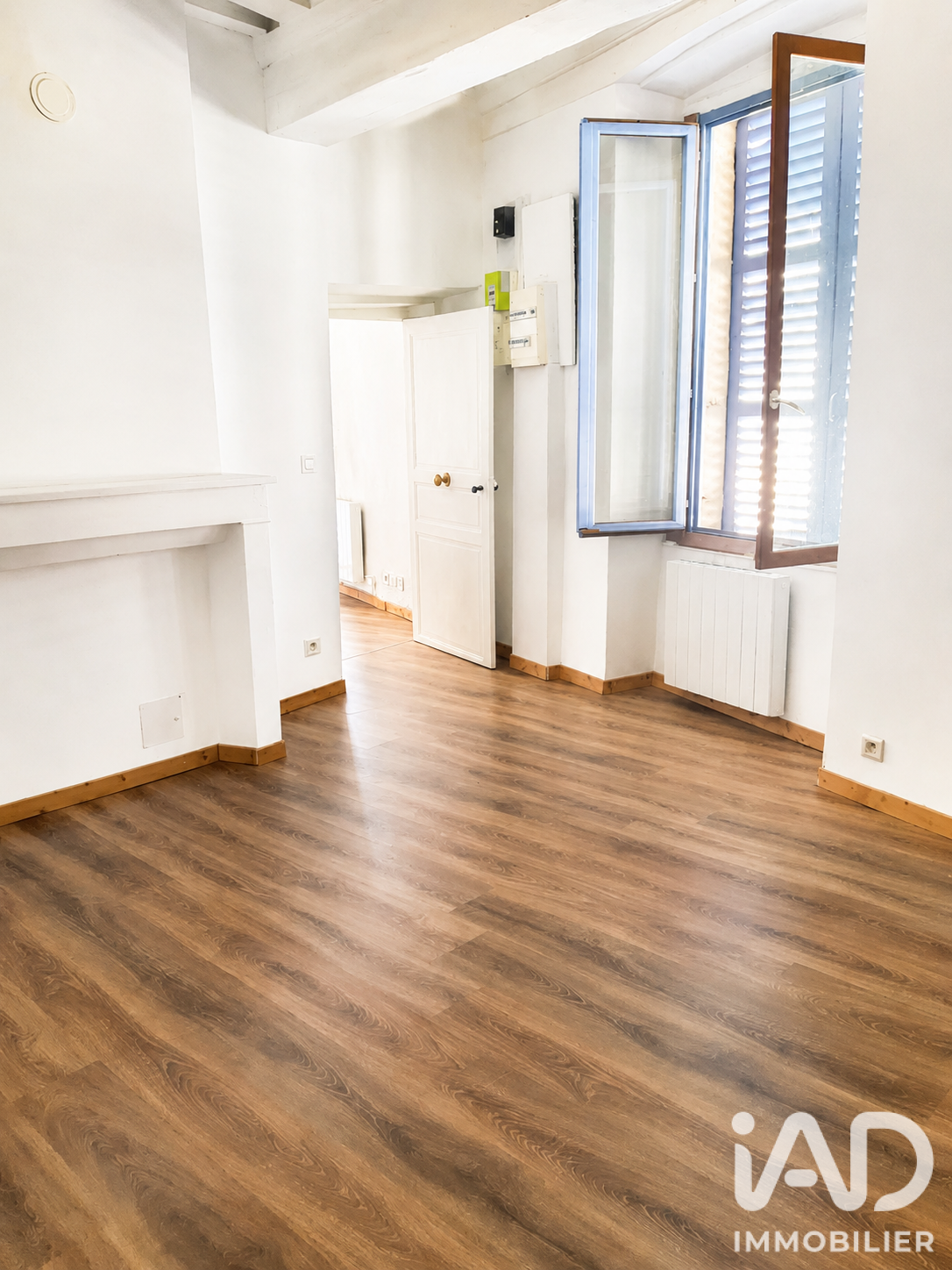 Séjour d'un T2 rénové avec sol PVC imitation bois et poutres apparentes peintes